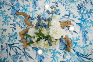 Photo of driftwood with white hydrangea and blue floral over blue coral linen